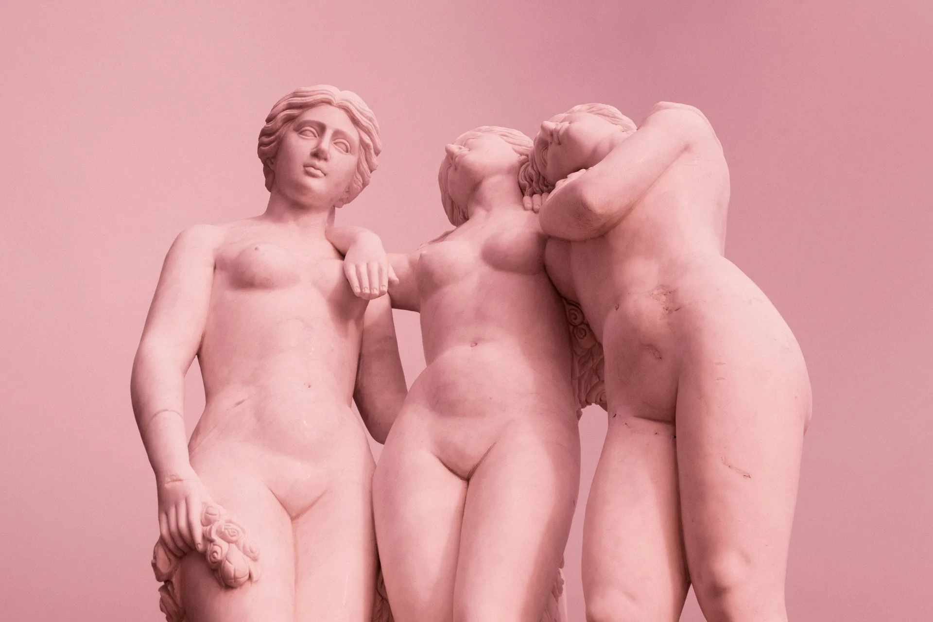Escultura clássica de três figuras, em tons de rosa